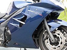 サイドカウルのエアアウトレットは従来どおりだが、車名ロゴがニューデザインになっている。φ43mmカートリッジ式正立フォークも従来どおり。