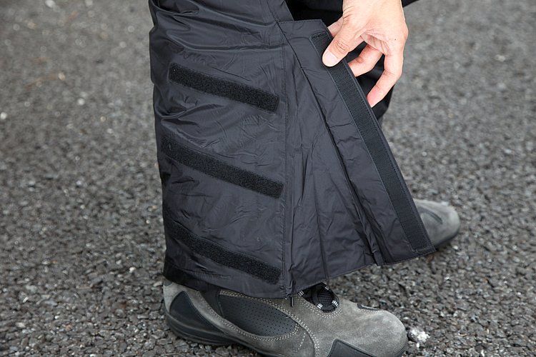 パンツ裾部は大きく開口し、オフロード用ブーツを着用したままでも着脱できる。フラップは上下3段のベルクロどめ。裾内側は素材を二重にしており、エンジンの熱によるダメージを防ぐ。