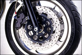 φ36→43mmのフォークは後期型XJR1200がベースで、全長が確保され調整機構も揃う利点が強み。三ツ又は同店製削り出しトップブリッジ＋GSF1200用アンダーブラケット。φ320mmブレーキディスクはGSX-R750（T）でFキャリパーはスミトモ6P（ここは時代、の部分）