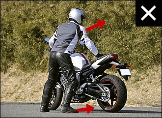 バイクに対して体の正面を向けて立つと、押すときに右手に力が入りにくくなります。また「カニ歩き」になりがちで、足がもつれるなどかえってバランスを崩しやすくなるので注意。左写真と上体や爪先の向きを比べてみてください。