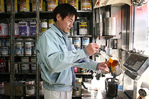 調色ブースで塗料の調整を続ける２代目社長の岡島史郎さん。先代から45年に渡り、経験が蓄積され続けている。