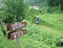 美郷町酒谷番所跡附近の石見銀山街道の市古道を激走（？）する飛脚便。重い義援金を持って真夏の峠越えは大変だ。飛脚は汗びっしょりになって黙々と走っている。