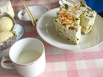 本日の朝食は菜豆腐と、できたて豆乳。椅子に座ったら、ほかにもいろいろ出てきました。おばあちゃんと一緒に朝食をいただきました。うめ～。